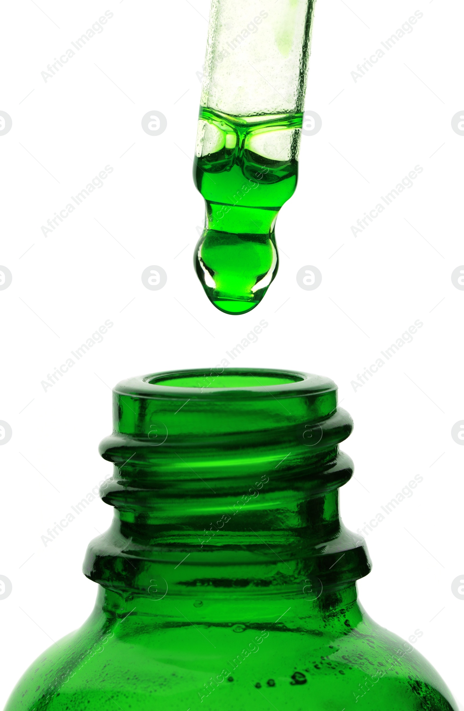 Photo of Dripping green facial serum from pipette into glass bottle on white background, closeup