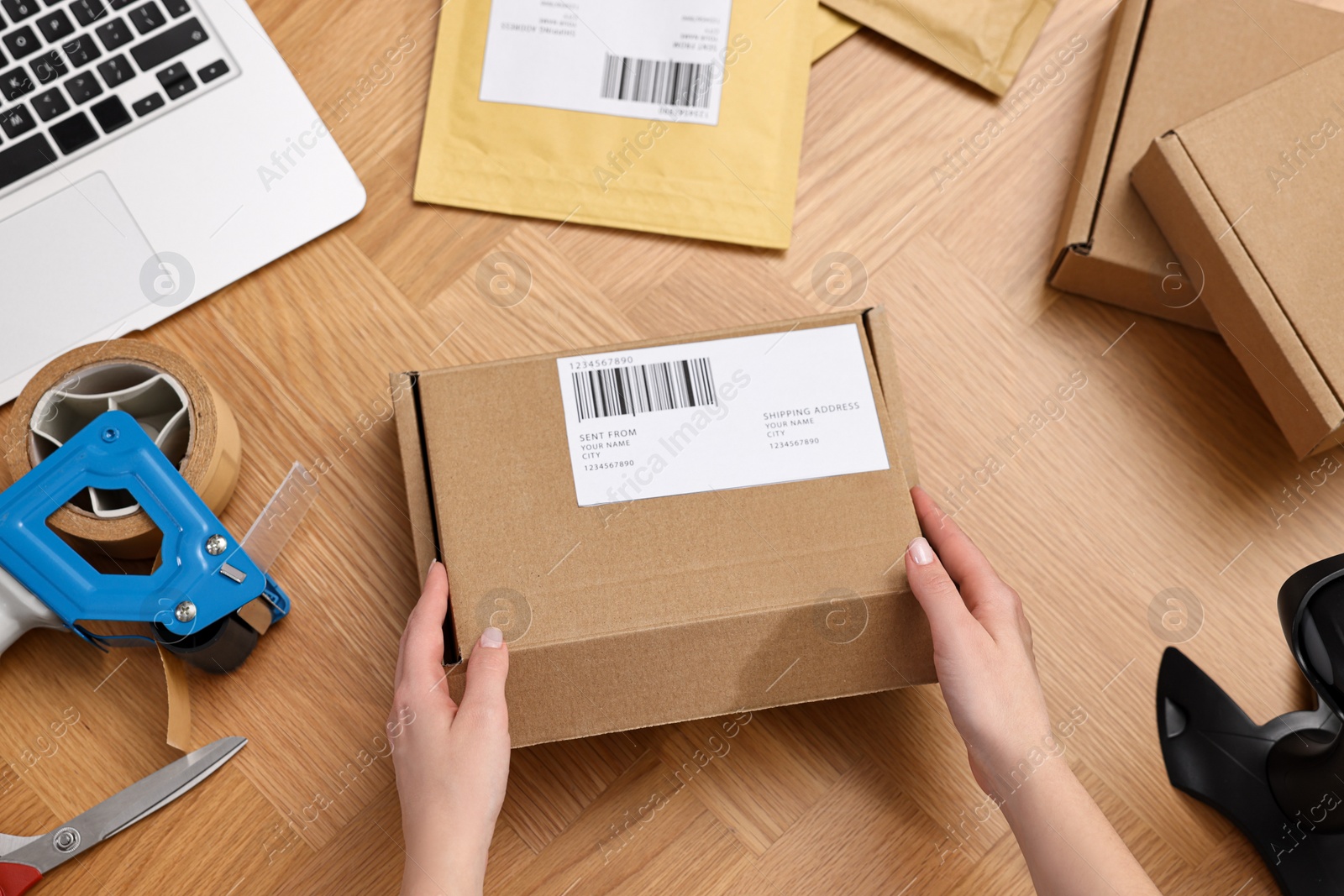 Photo of Post office worker packing parcel at wooden table, top view