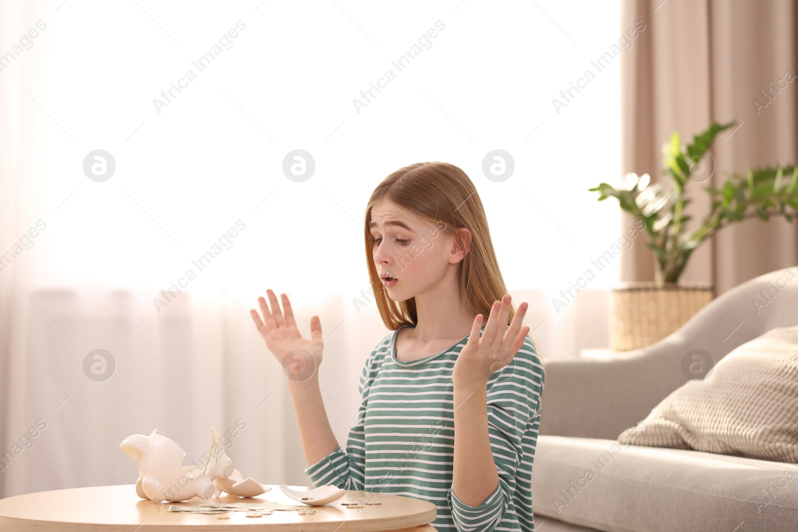 Photo of Sad teen girl with broken piggy bank and money at home