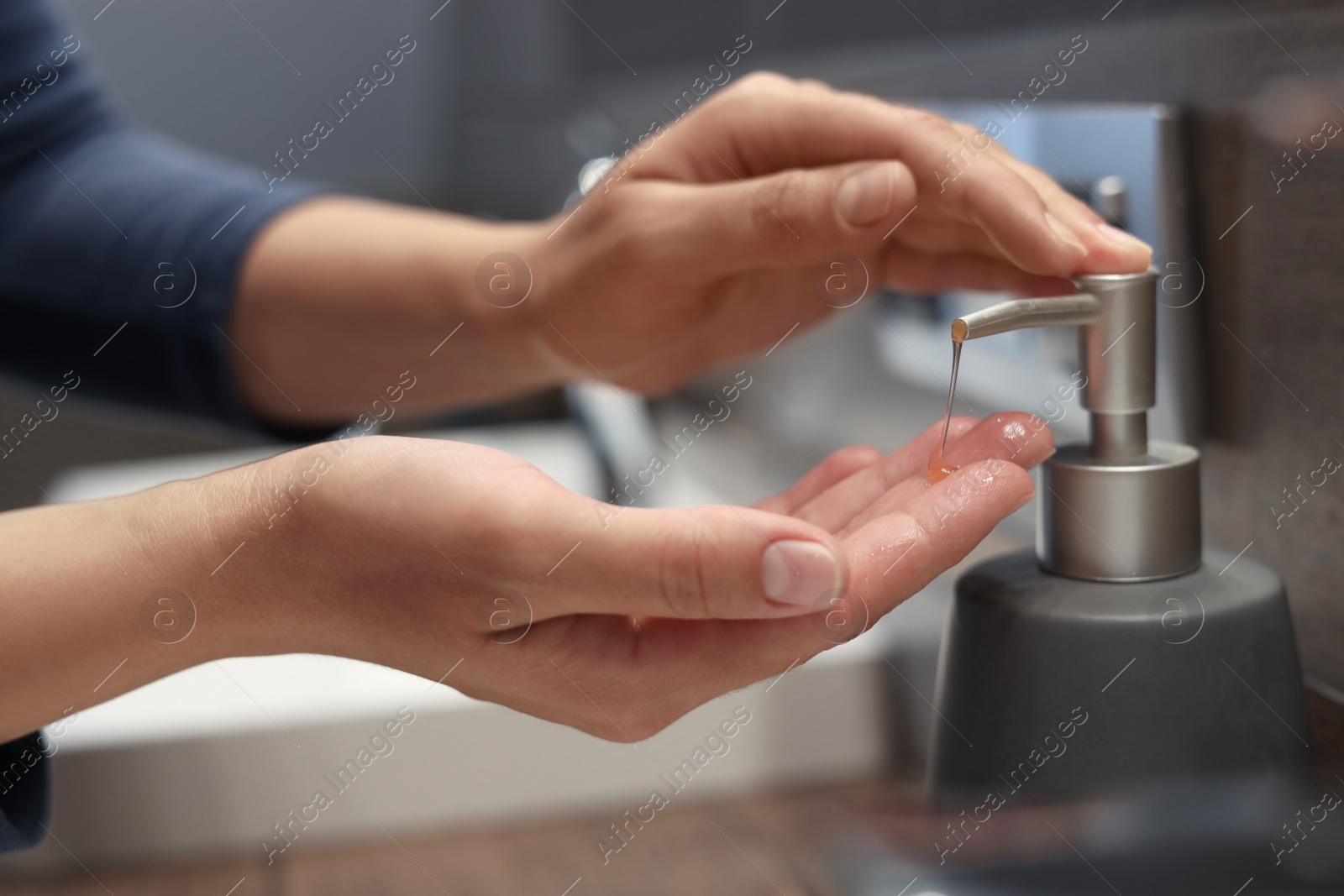 Photo of Woman using liquid soap dispenser in bathroom, closeup