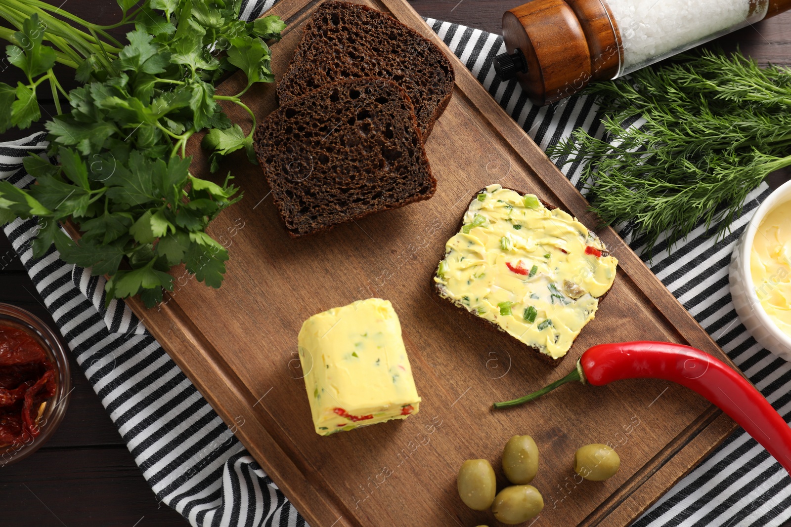 Photo of Tasty butter, bread and other ingredients on wooden table, top view