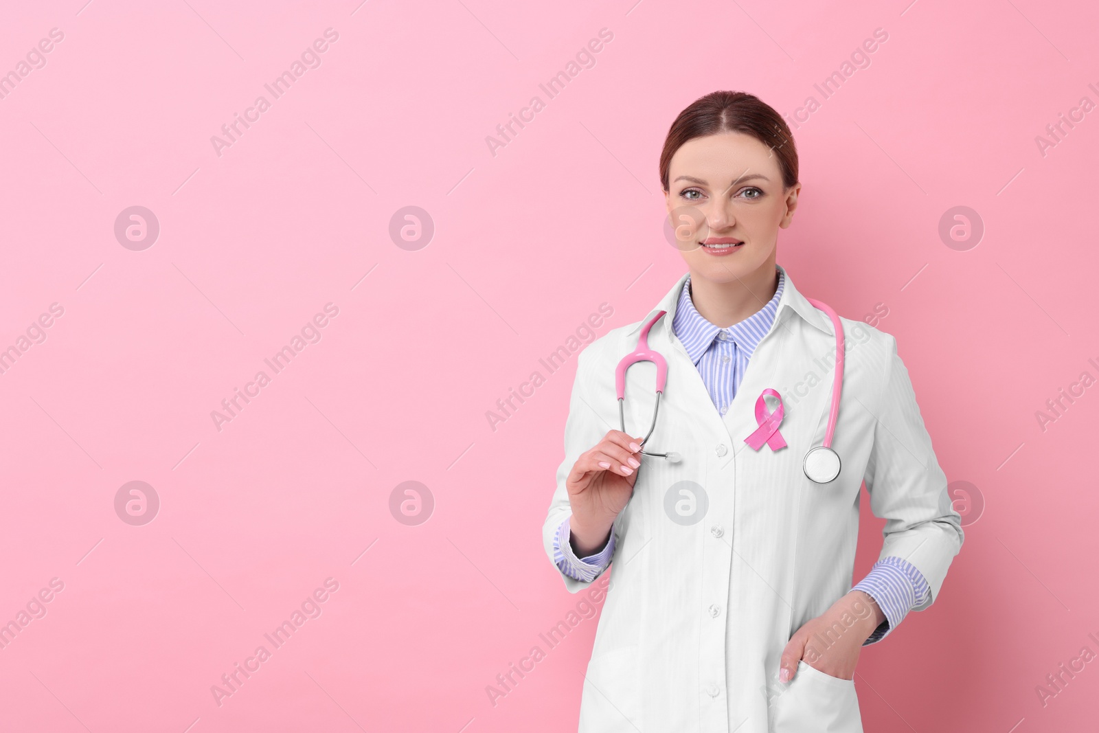 Photo of Mammologist with pink ribbon on color background, space for text. Breast cancer awareness