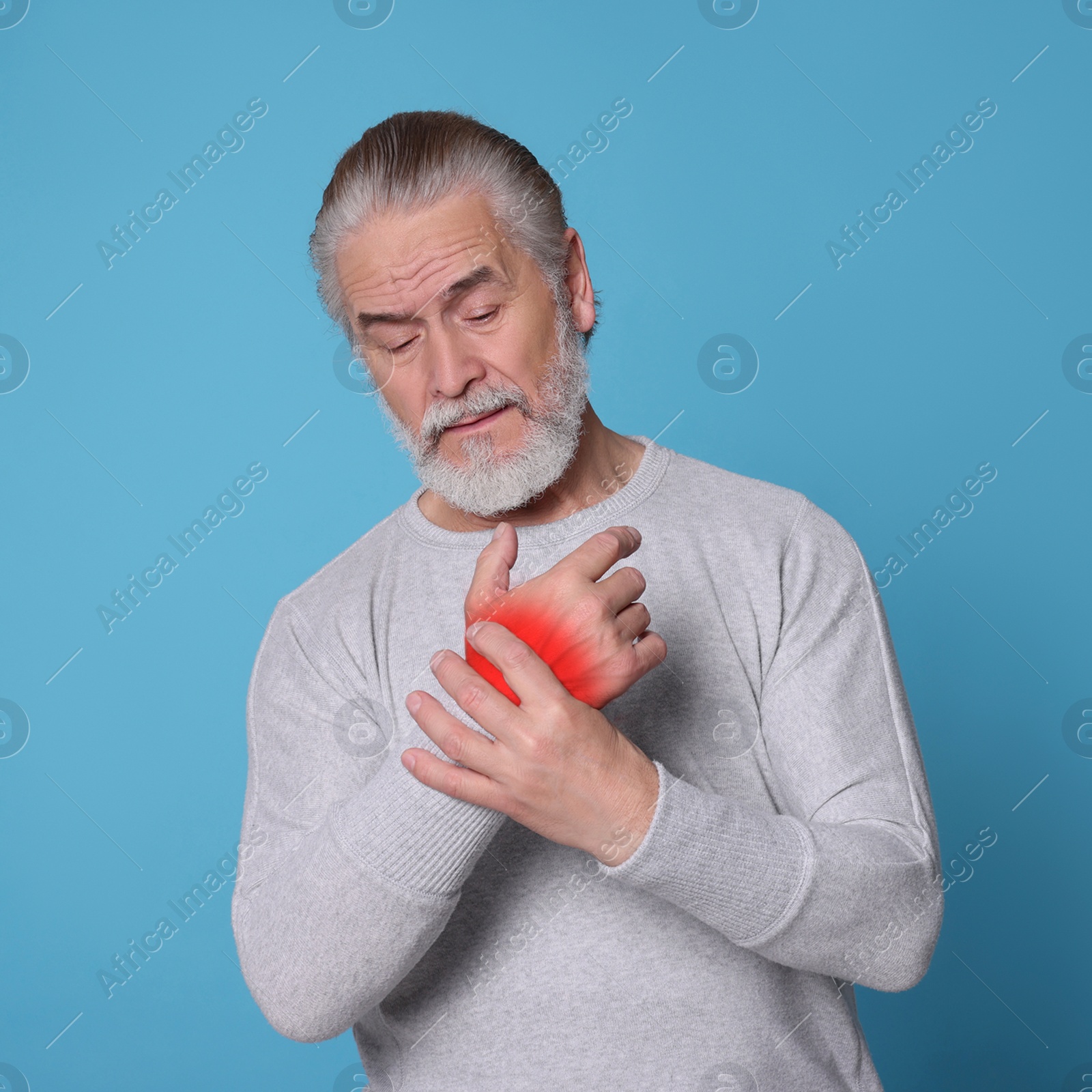 Image of Senior man suffering from rheumatism on light blue background