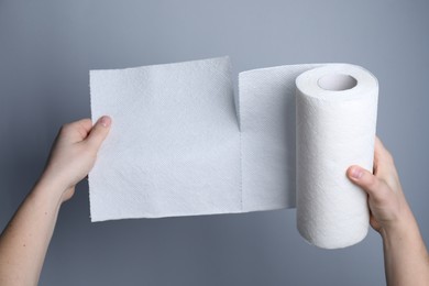 Photo of Woman tearing paper towels on grey background, closeup
