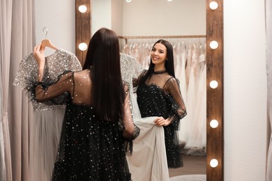 Photo of Woman choosing dress in rental clothing salon