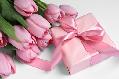 Beautiful gift box and bouquet of pink tulip flowers on white background, closeup