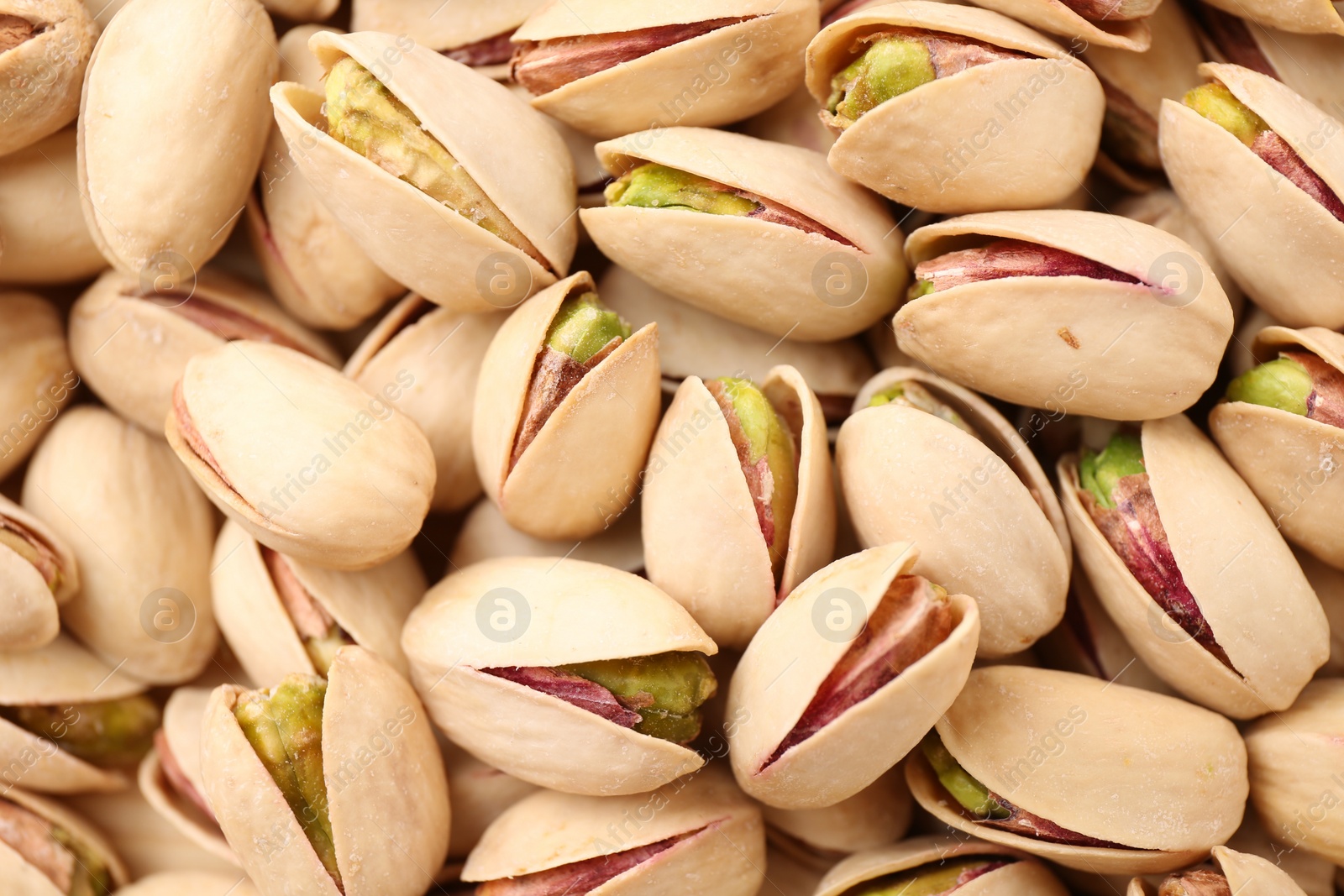 Photo of Tasty unpeeled pistachios as background, top view