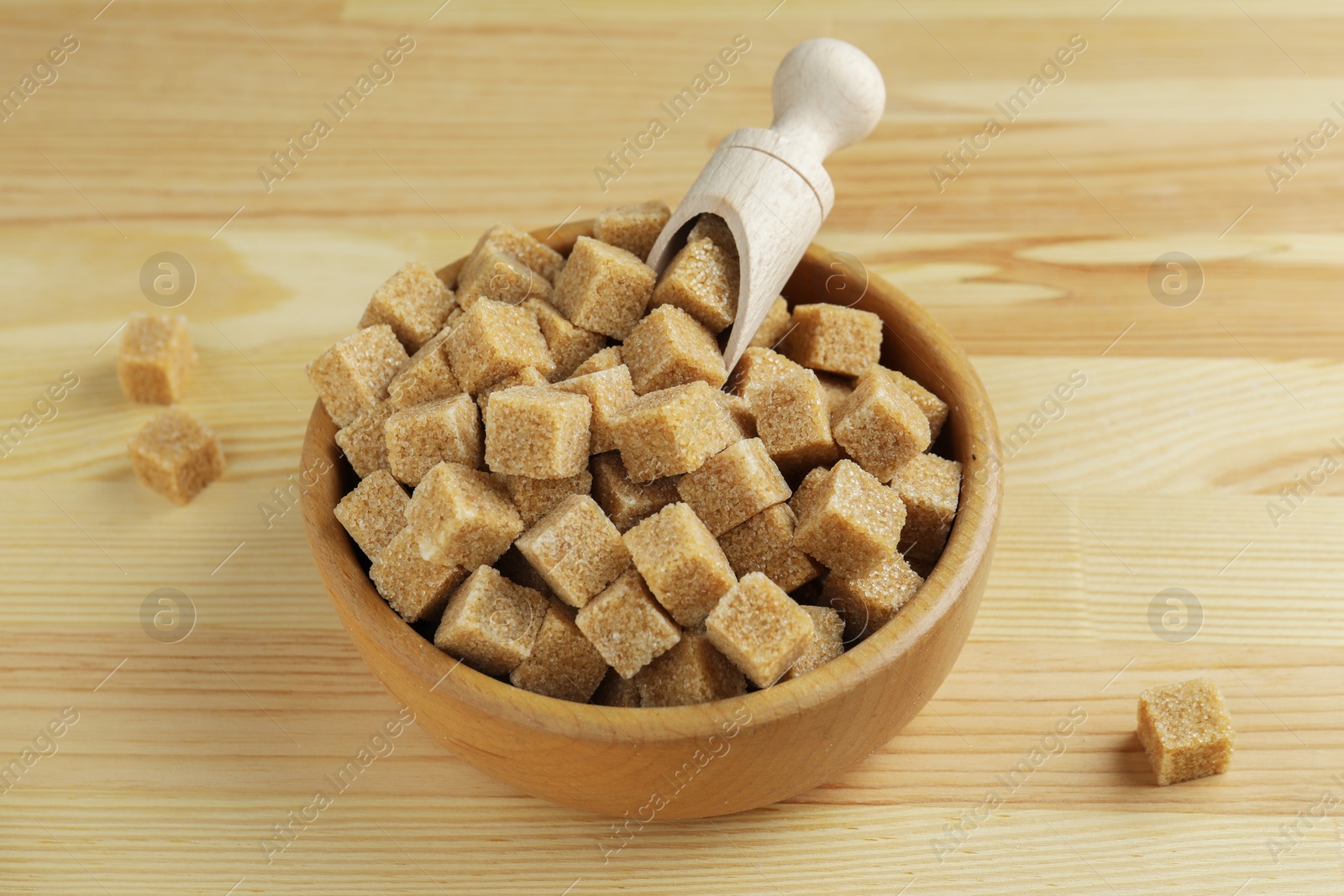 Photo of Brown sugar cubes in bowl on wooden table