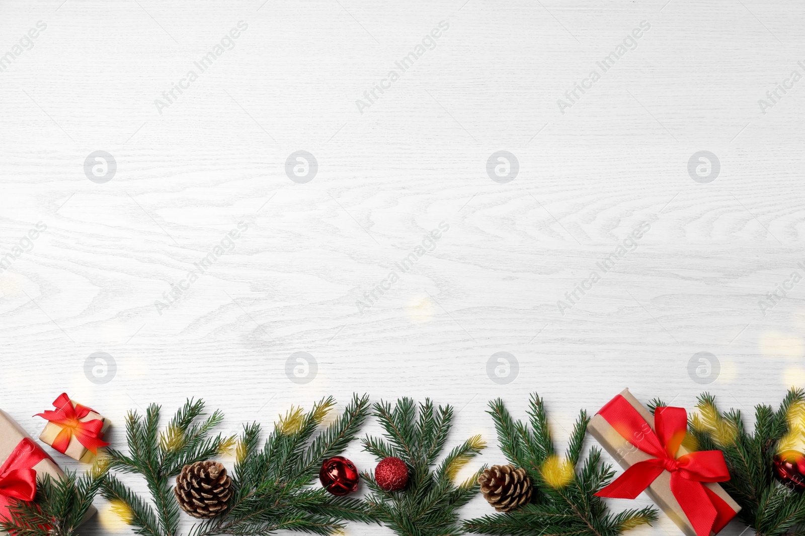 Photo of Christmas greeting card with space for text. Flat lay composition of fir tree branches and festive decor on white wooden background