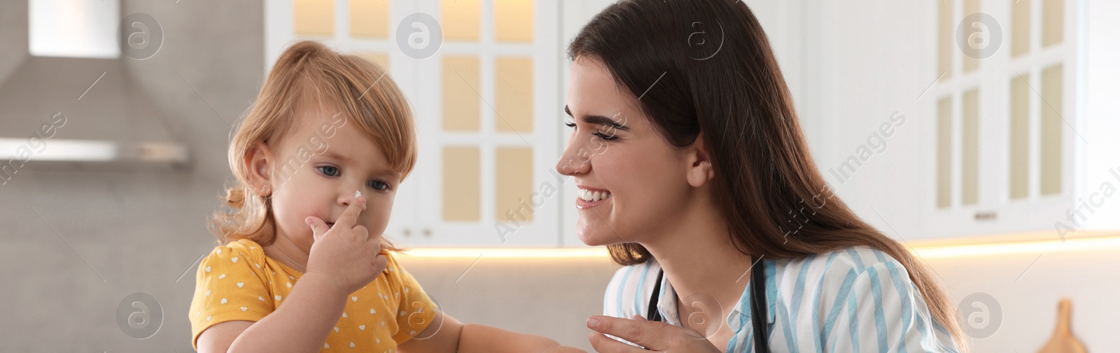 Image of Mother and her little daughter cooking together in kitchen, banner design