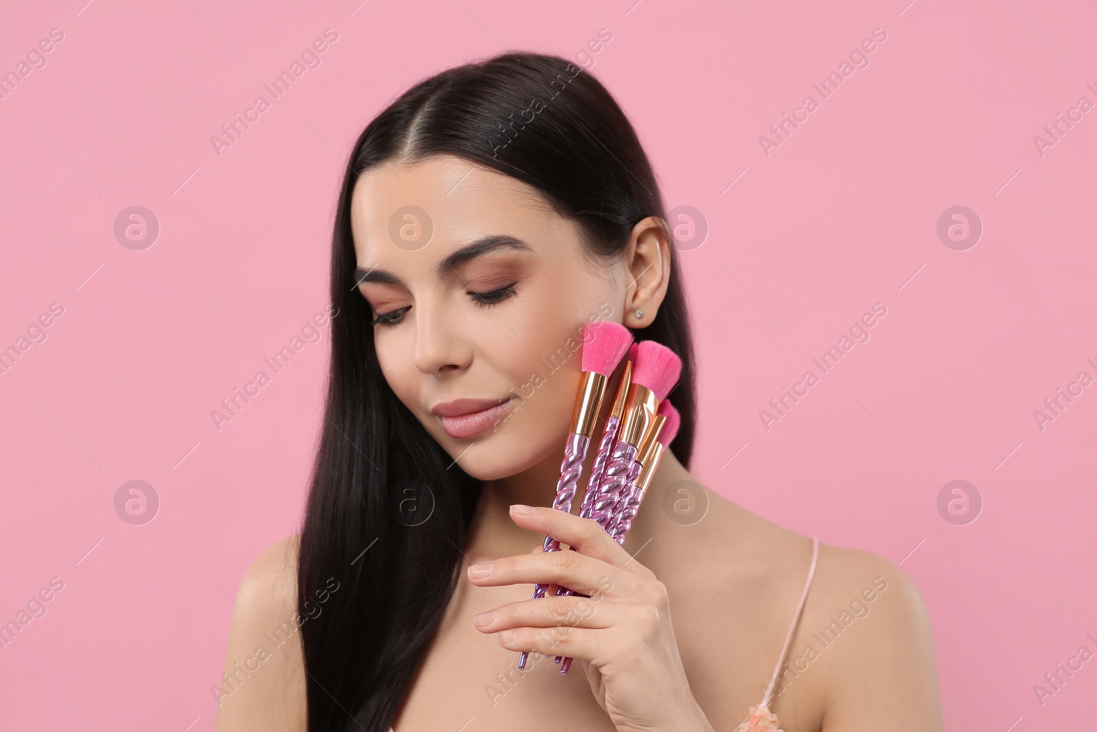 Photo of Beautiful woman with different makeup brushes on pink background