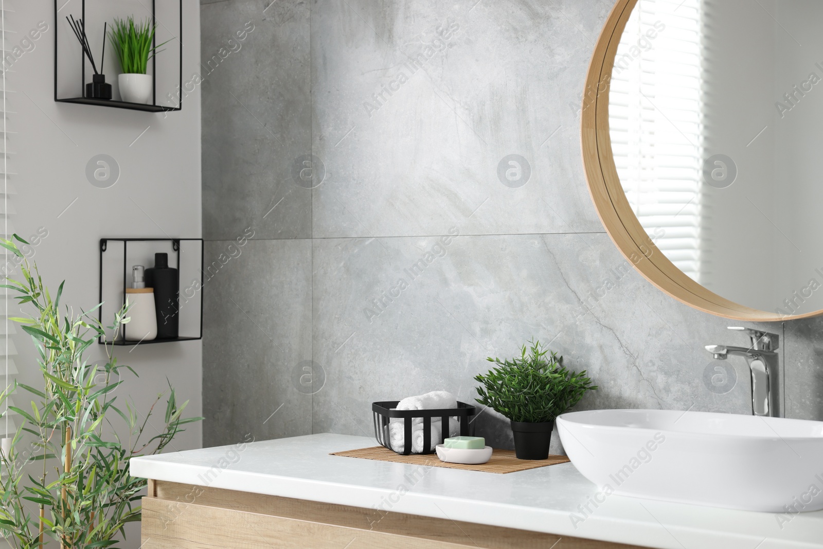 Photo of Potted artificial plants, rolled towels and soap near sink on bathroom vanity