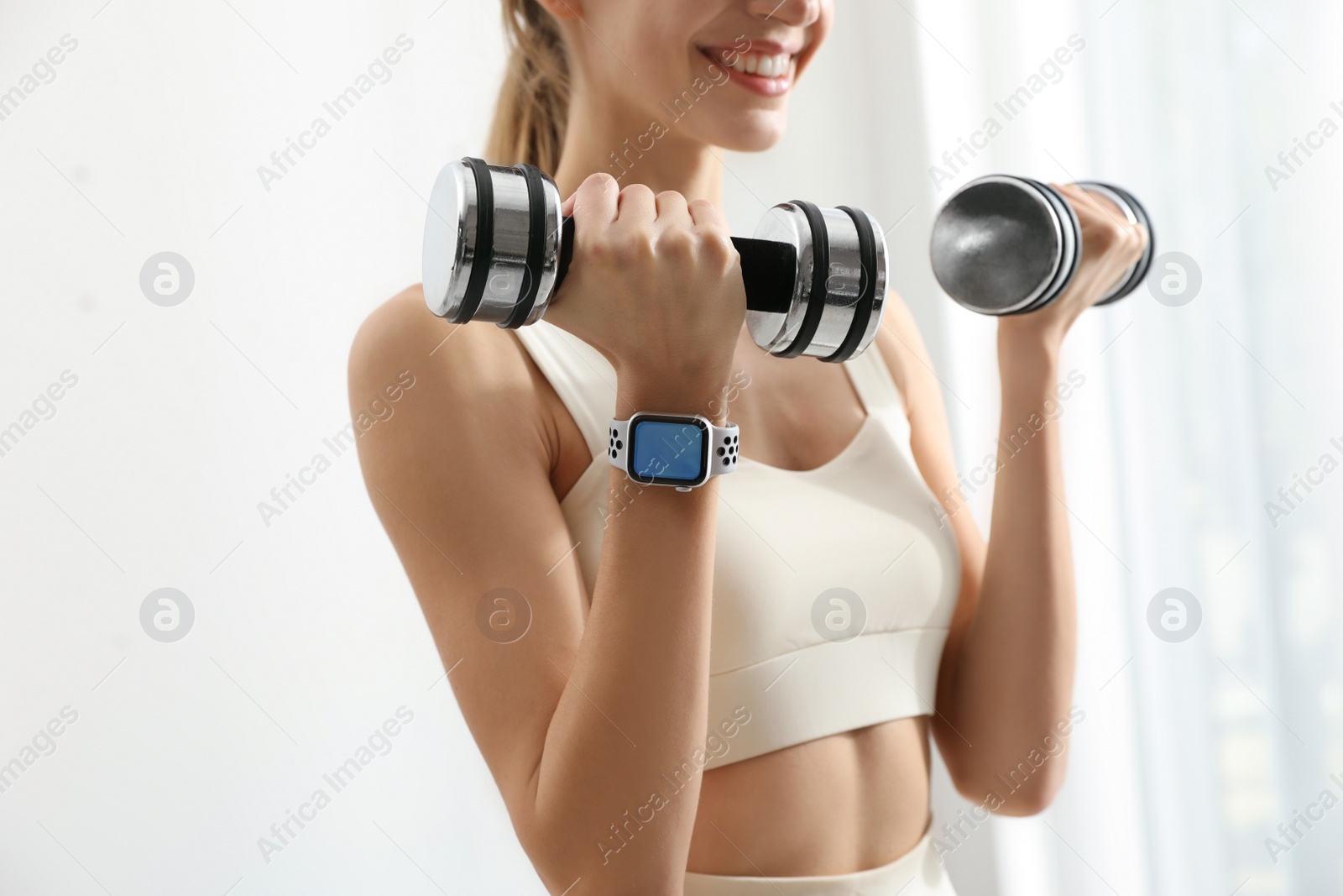 Photo of Young woman wearing smart watch during training indoors, closeup