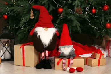 Photo of Cute Christmas gnomes on floor near tree and gift boxes at home