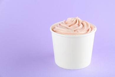 Cup with tasty frozen yogurt on violet background. Space for text