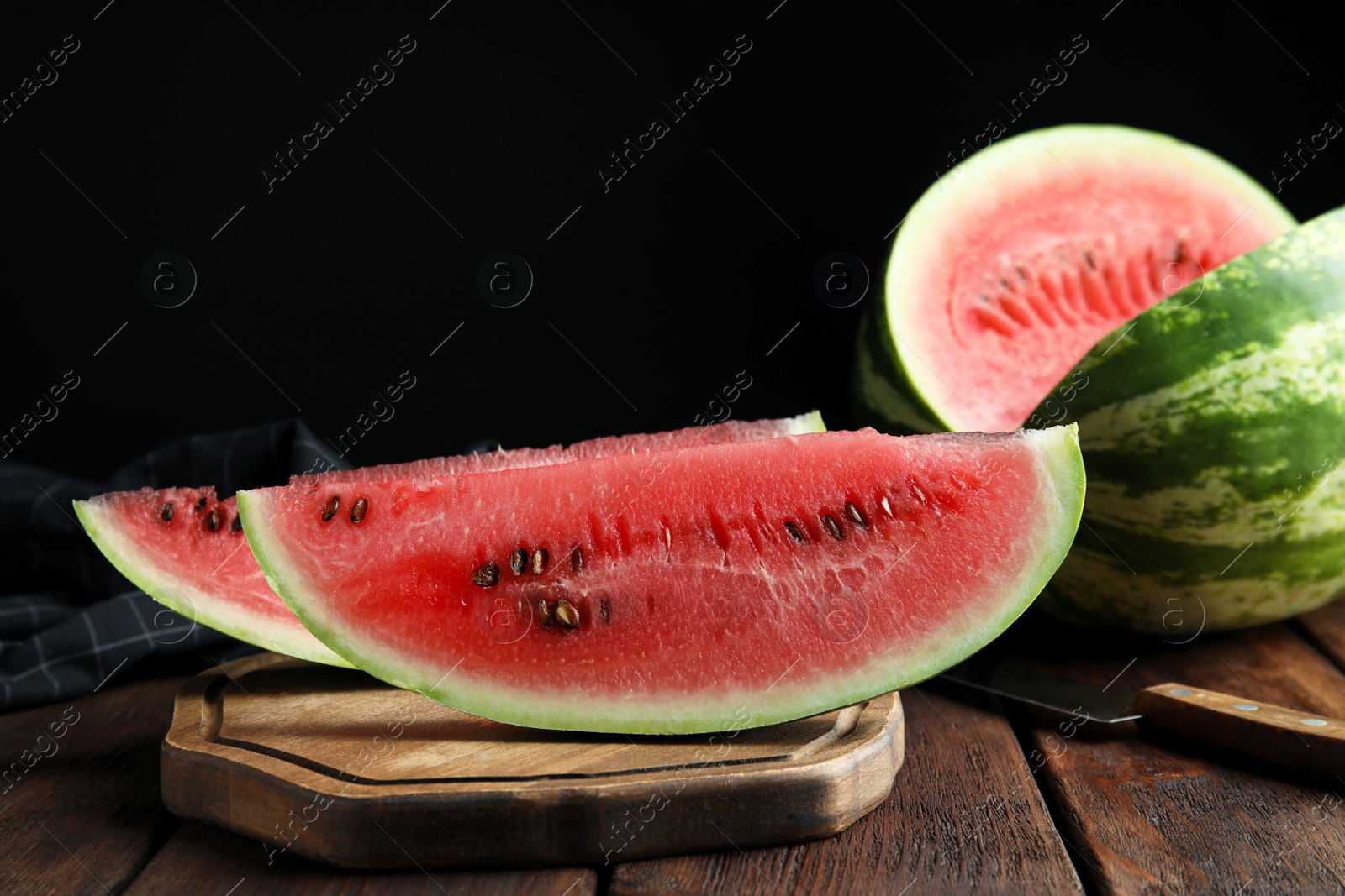 Photo of Yummy watermelon on wooden table against black background