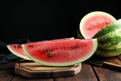 Photo of Yummy watermelon on wooden table against black background