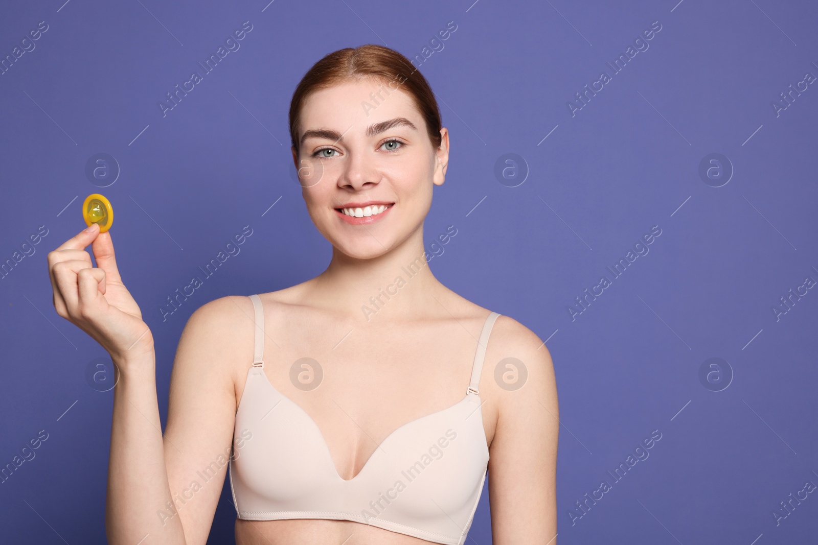 Photo of Woman in bra holding condom on purple background, space for text. Safe sex