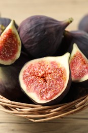 Whole and cut ripe figs on wooden table, closeup