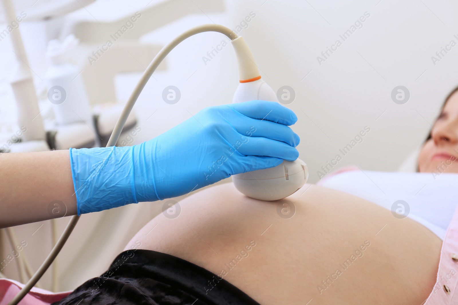 Photo of Pregnant woman undergoing ultrasound scan in clinic, closeup