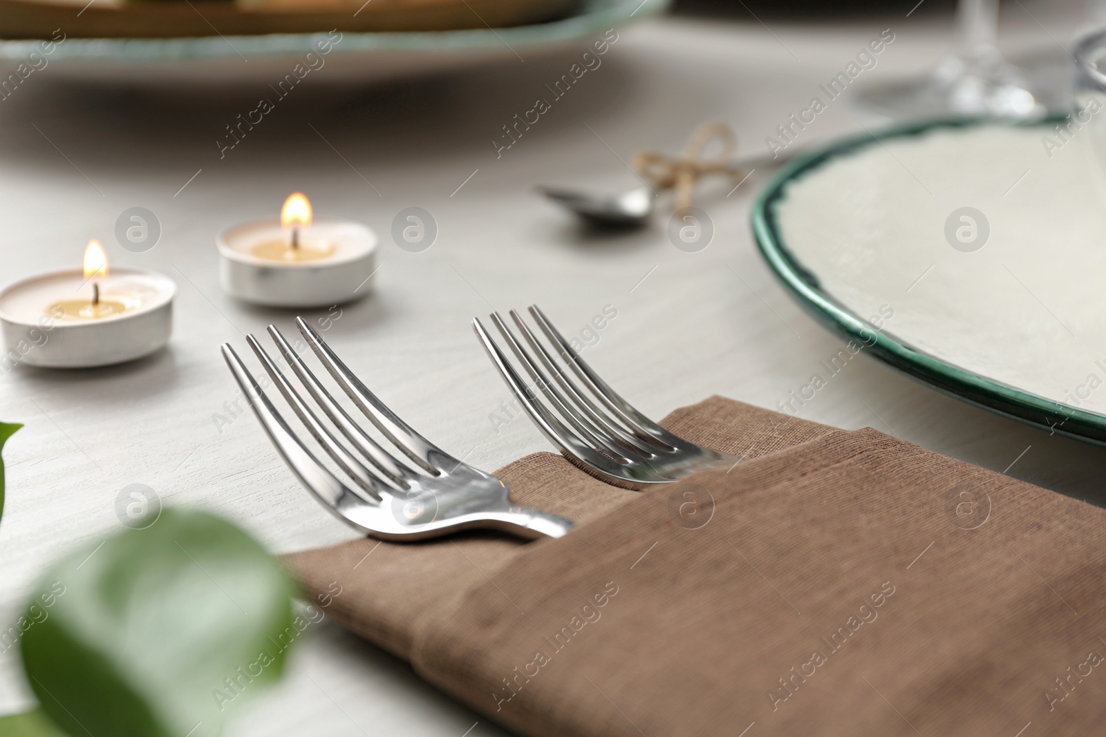 Photo of Elegant forks with napkin on table, closeup. Festive setting