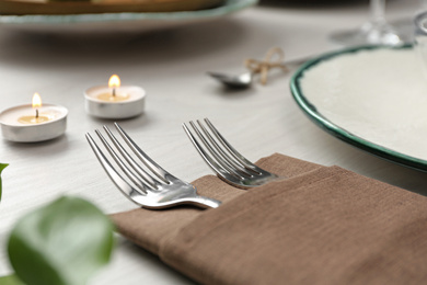 Elegant forks with napkin on table, closeup. Festive setting