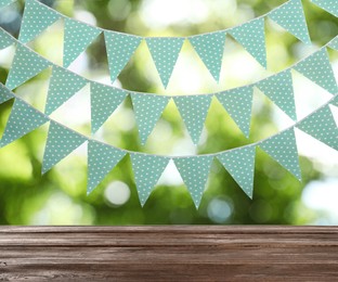 Empty wooden table and decorative bunting flags outdoors