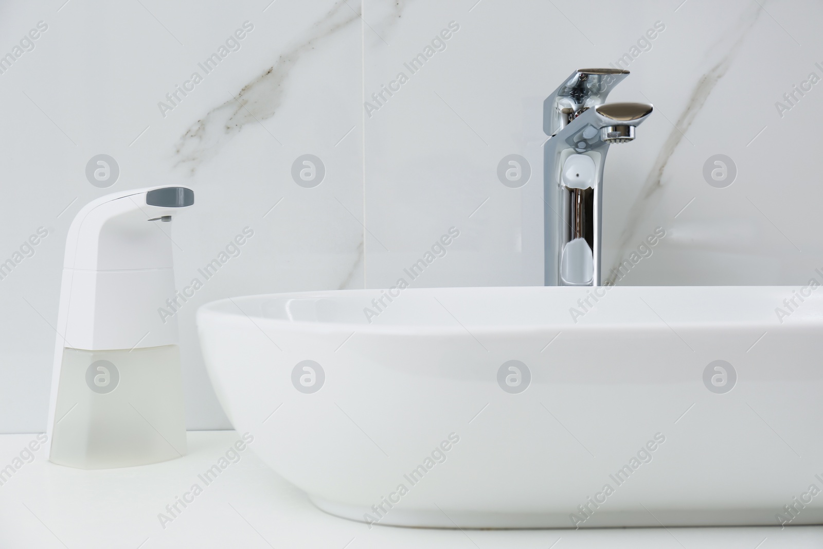 Photo of Modern automatic soap dispenser near sink in bathroom, closeup