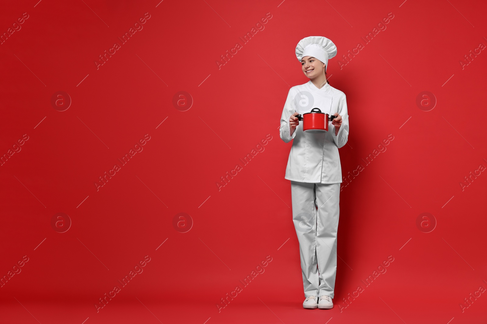 Photo of Professional chef with cooking pot on red background. Space for text