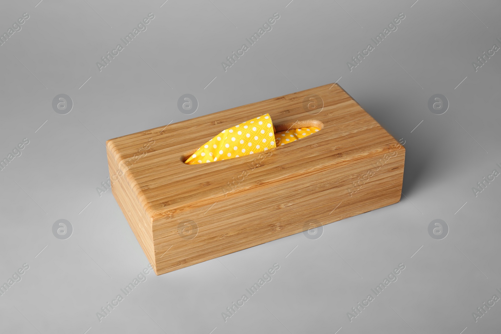 Photo of Wooden napkin holder with paper serviettes on gray background