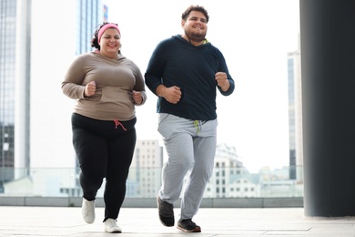 Photo of Overweight couple running together outdoors. Fitness lifestyle