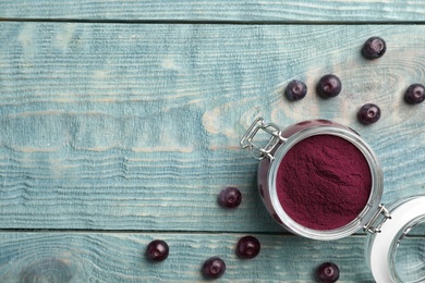 Photo of Jar of acai powder and fresh berries on wooden table, flat lay with space for text