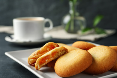 Tasty shortbread cookies with filling on black table, closeup