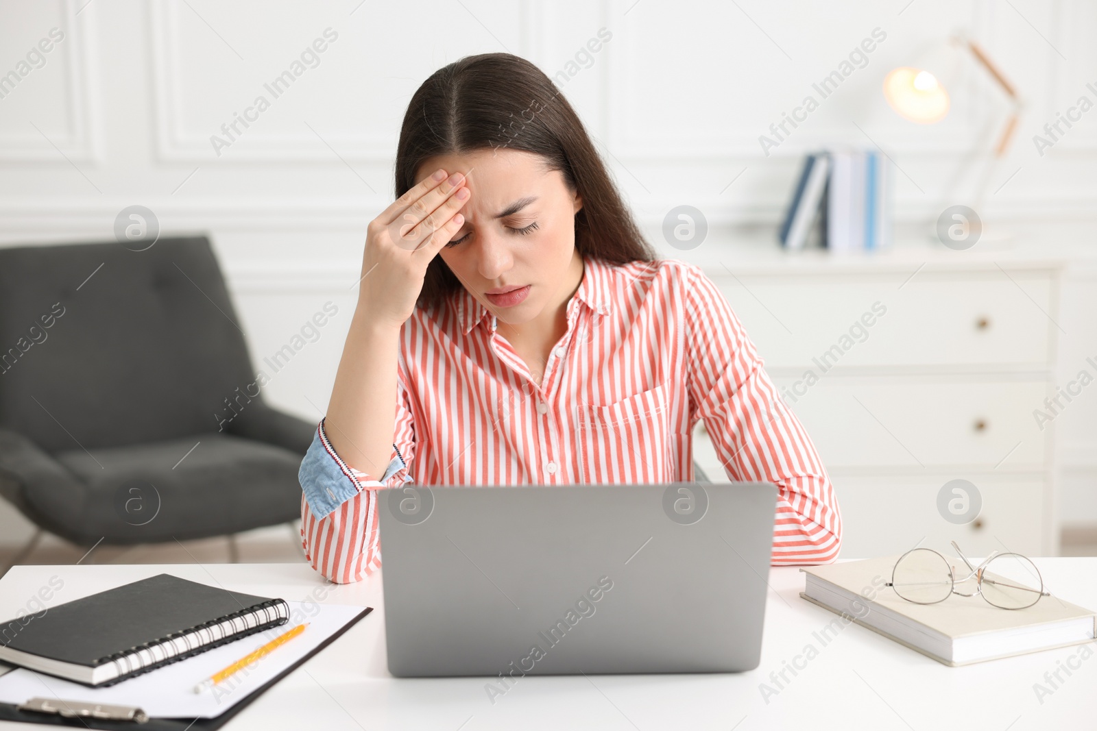 Photo of Young woman suffering from headache at workplace in office