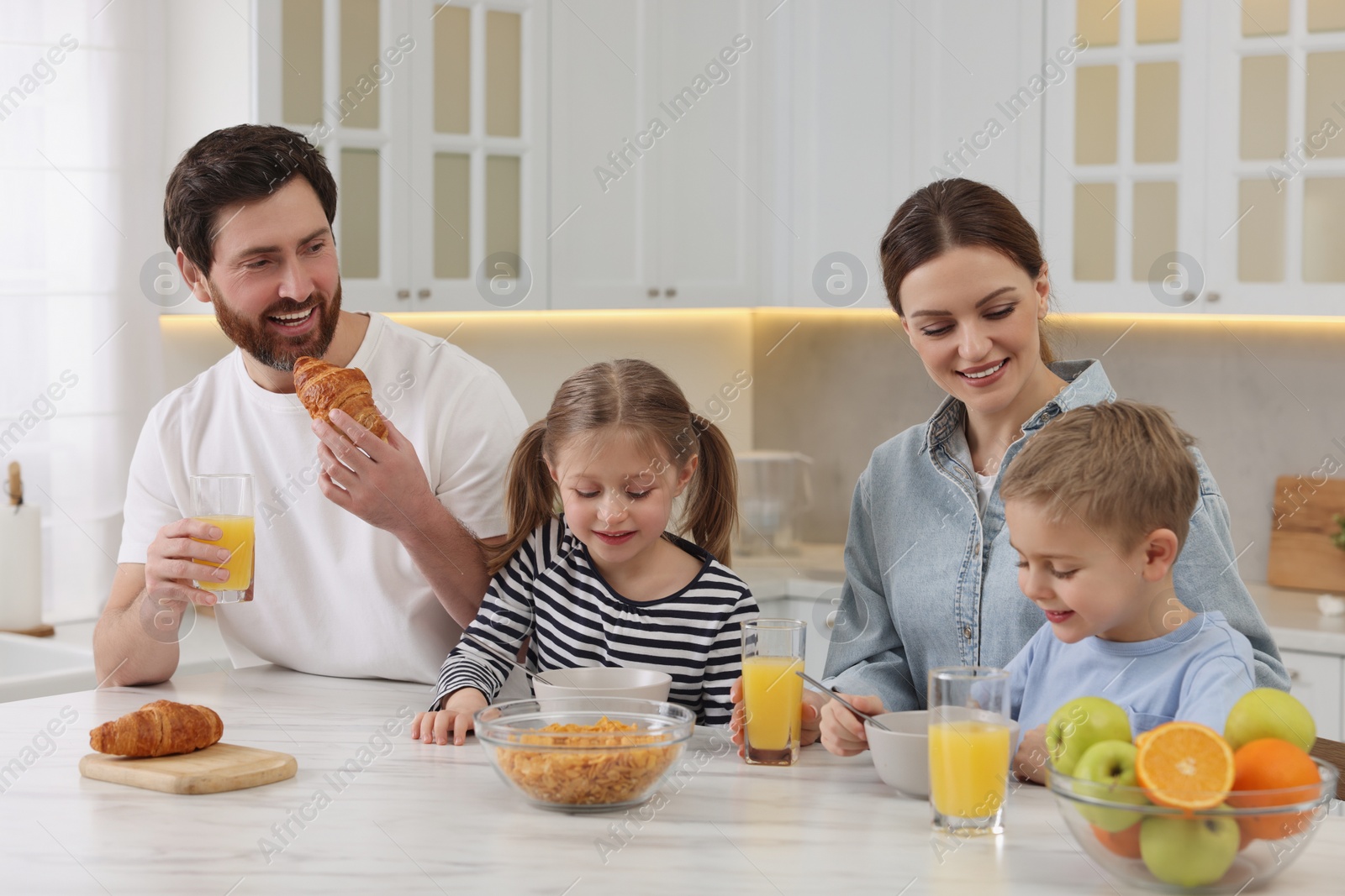 Photo of Happy family having breakfast at table in kitchen