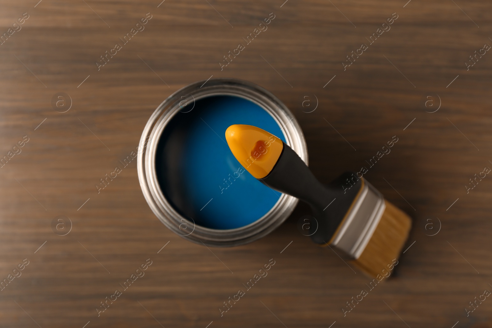 Photo of Can of blue paint and brush on wooden background, top view