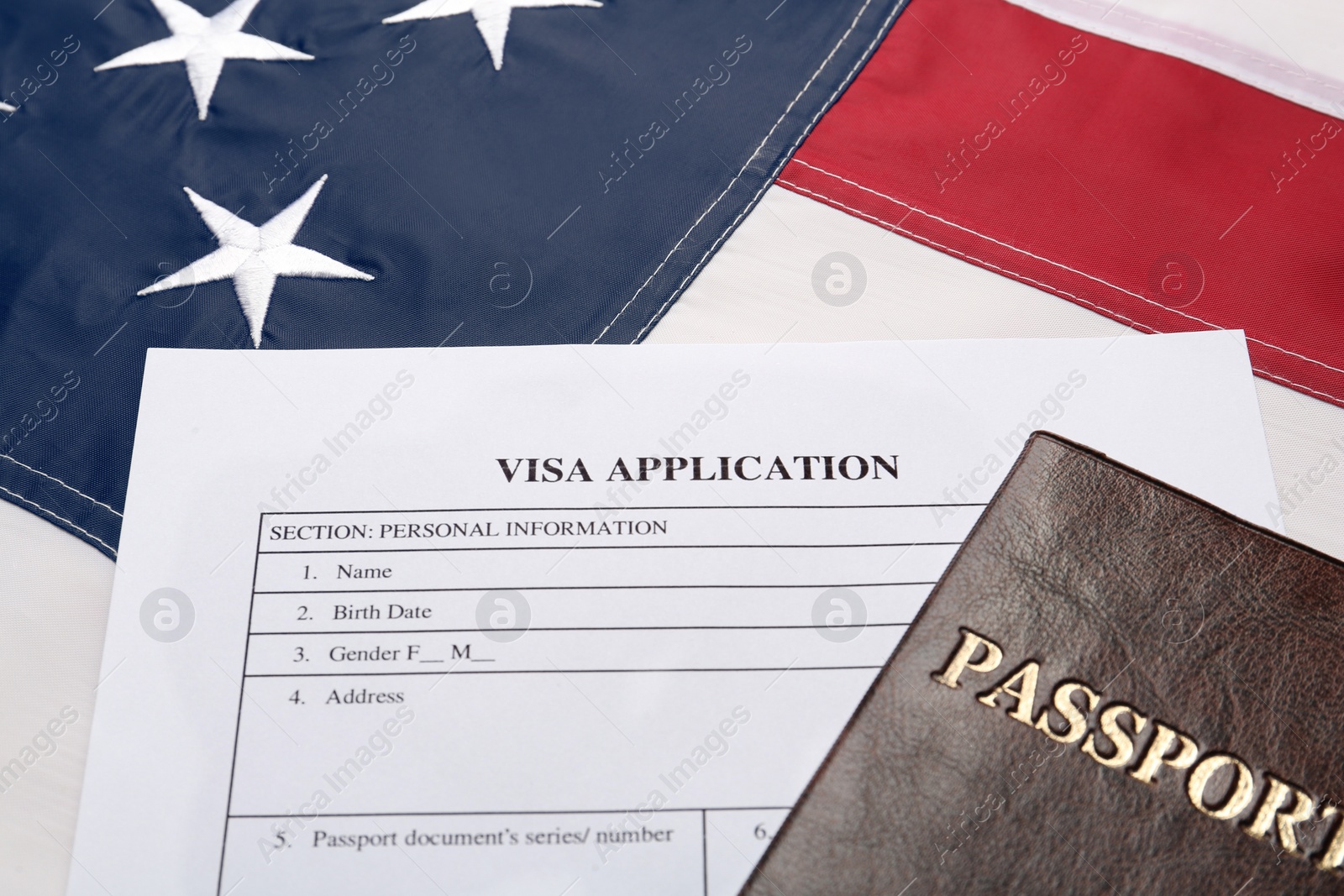 Photo of Visa application form and passport on American flag, closeup