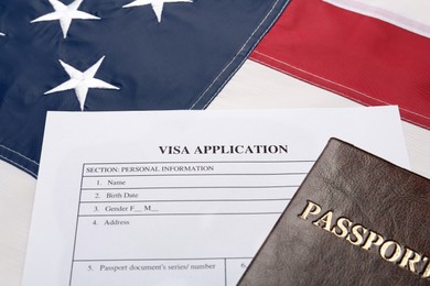 Photo of Visa application form and passport on American flag, closeup