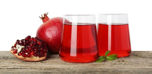 Photo of Refreshing pomegranate juice in glasses, leaves and fruits on wooden table against white background