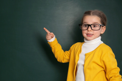 Photo of Cute little child wearing glasses near chalkboard. First time at school