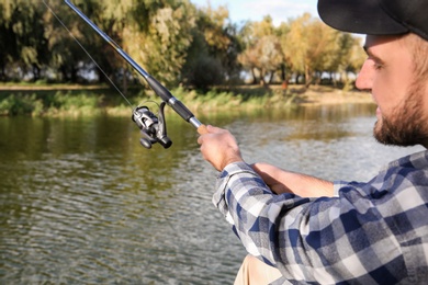 Photo of Man with rod fishing at riverside. Recreational activity