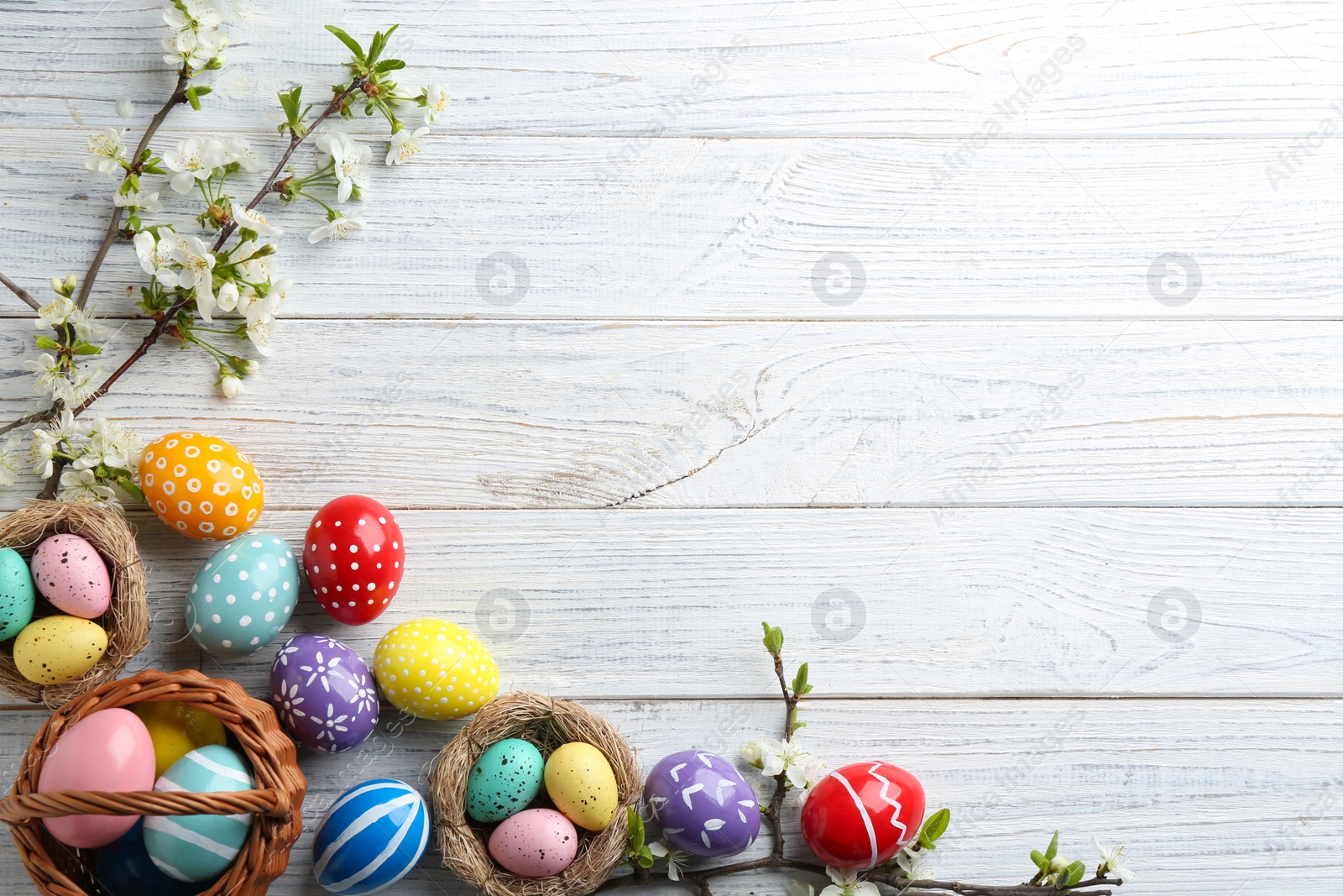 Photo of Flat lay composition with painted Easter eggs and blossoming branches on wooden background. Space for text