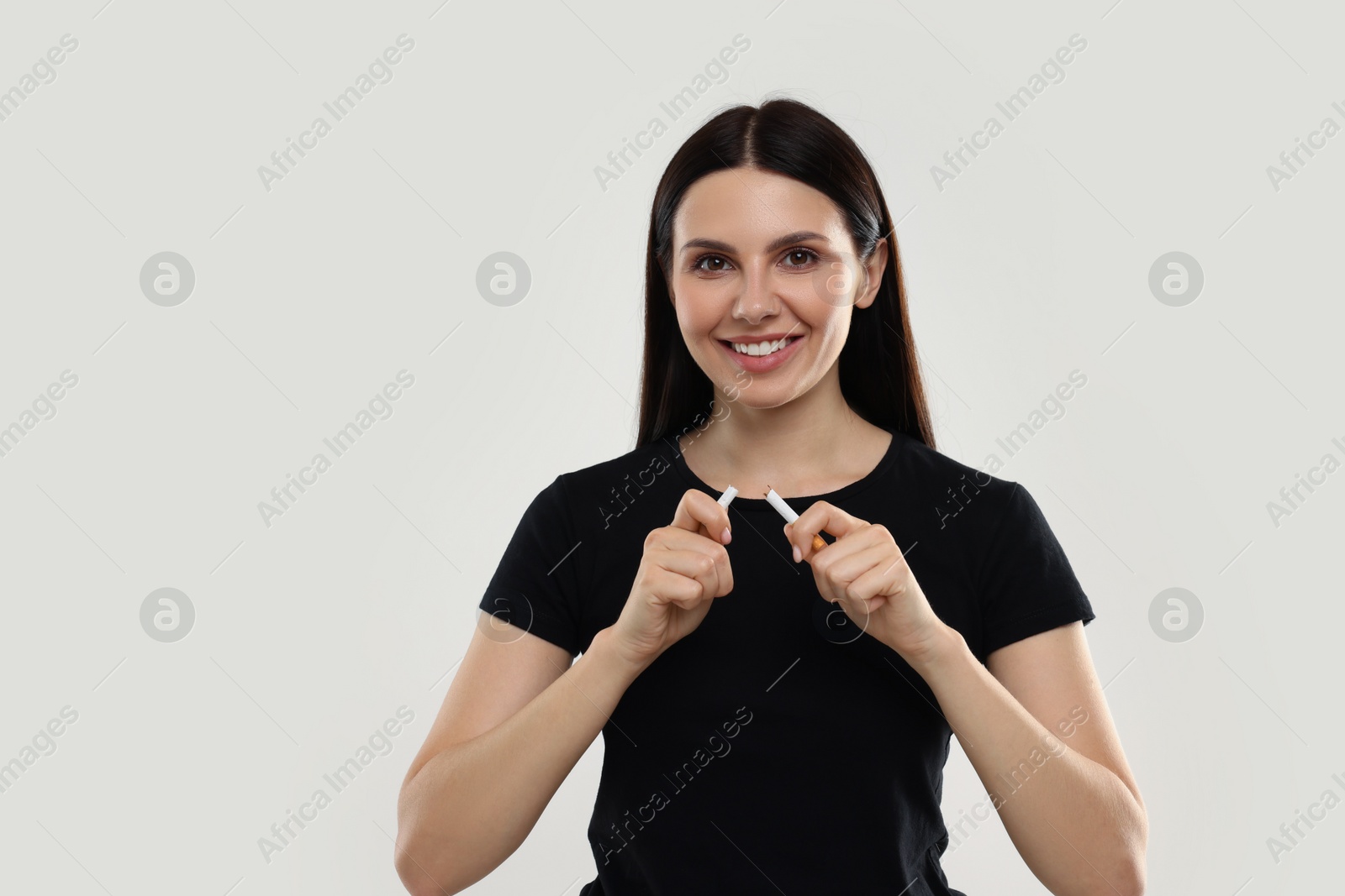 Photo of Stop smoking concept. Happy woman breaking cigarette on beige background, space for text