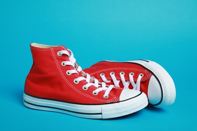 Pair of new stylish red sneakers on light blue background