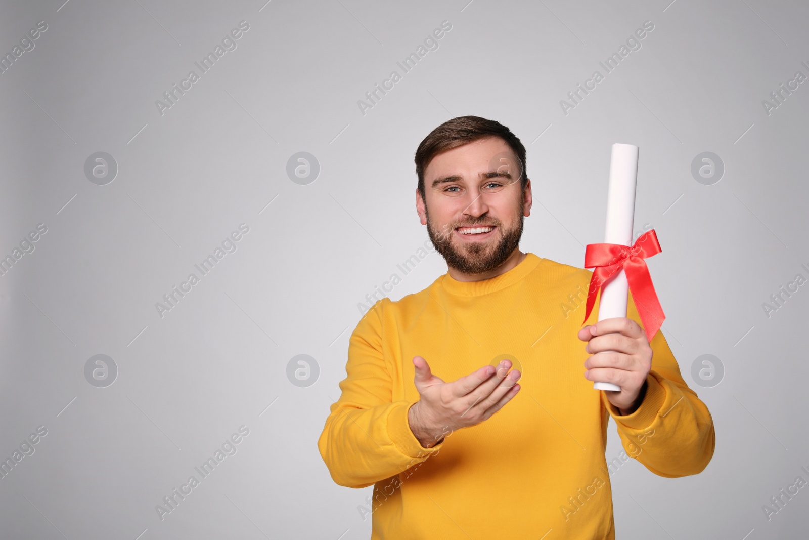 Photo of Happy student with diploma on light grey background. Space for text