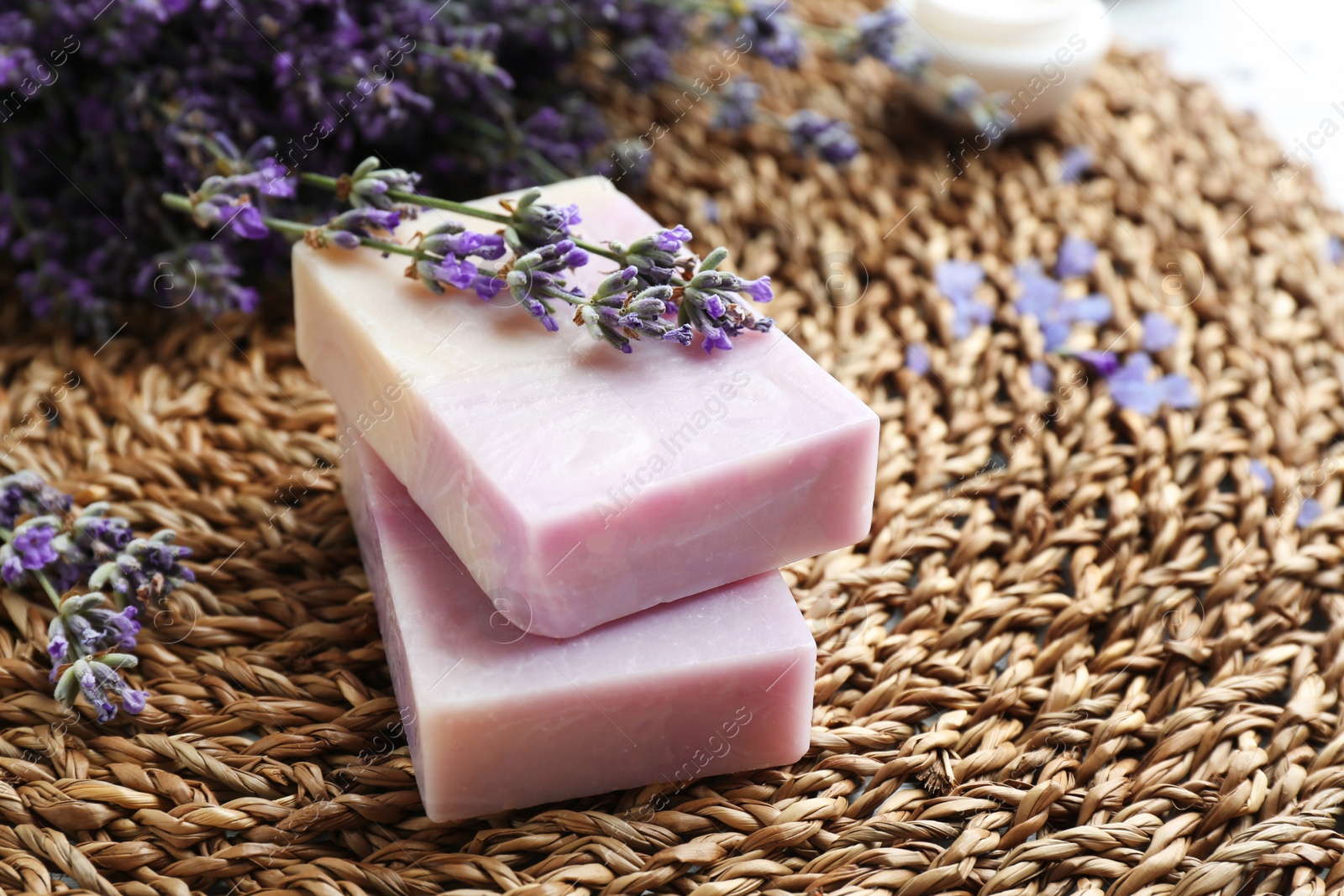 Photo of Handmade soap bars with lavender flowers on wicker mat, closeup. Space for text