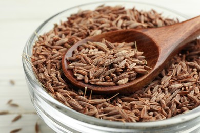 Photo of Bowl of caraway seeds and spoon on table, closeup