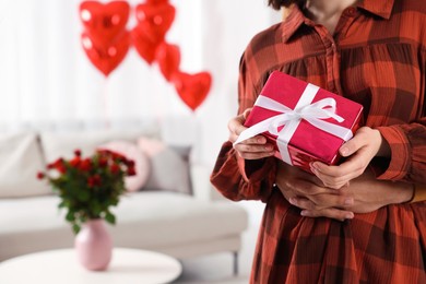 Photo of Happy couple celebrating Valentine's day. Beloved woman with gift box in room, space for text