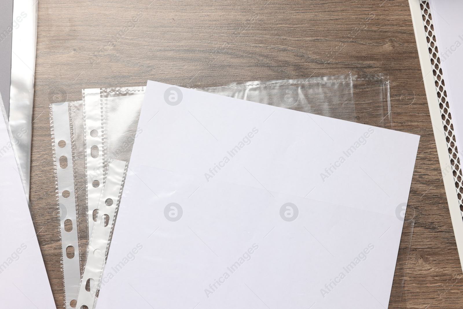 Photo of Punched pockets with paper sheet on wooden table, flat lay