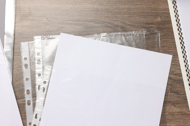 Photo of Punched pockets with paper sheet on wooden table, flat lay